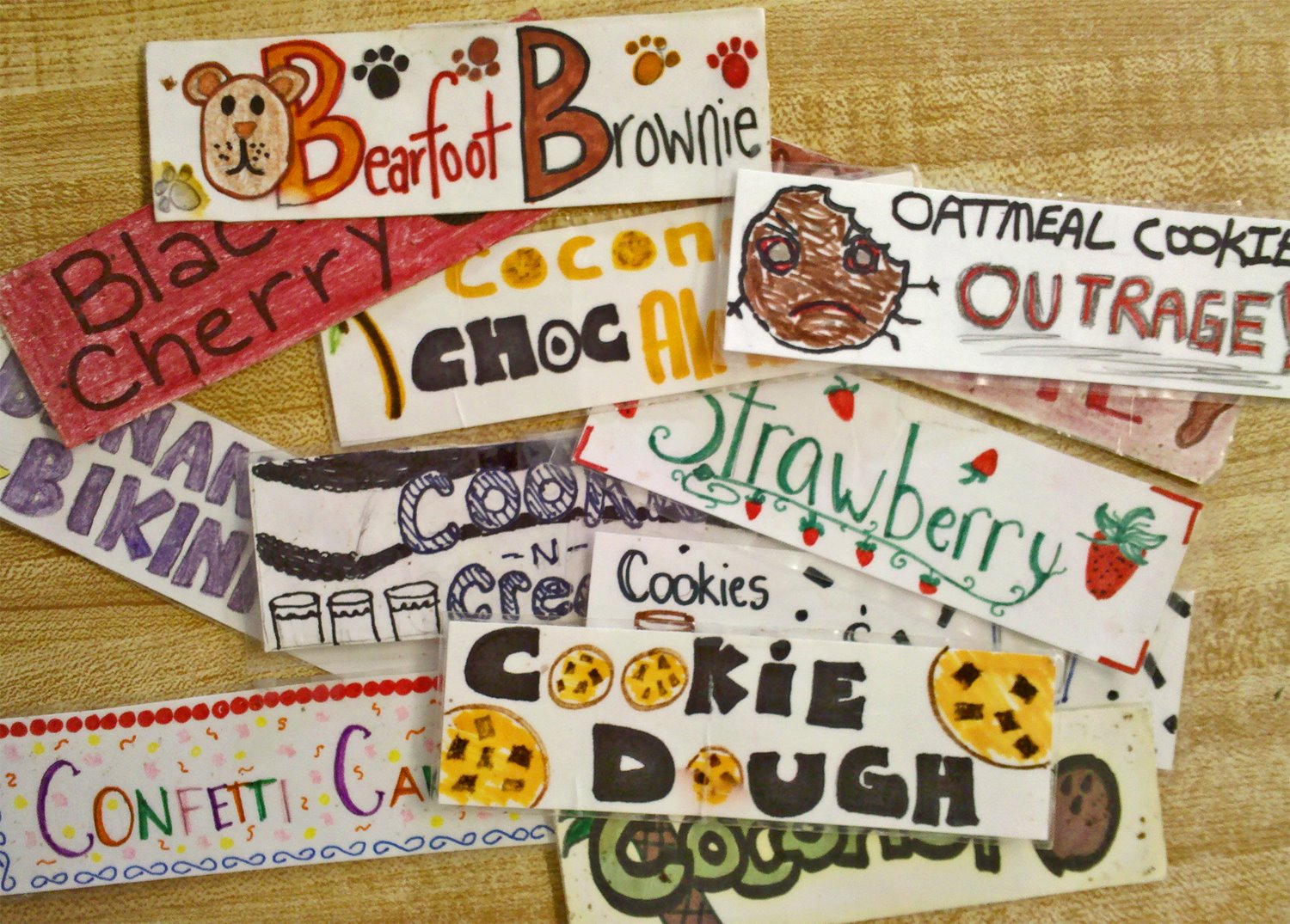 Various hand-drawn labels for ice cream flavors with names like Bearfoot Brownie, Oatmeal Cookie Outrage, Strawberry, and Cookie Dough