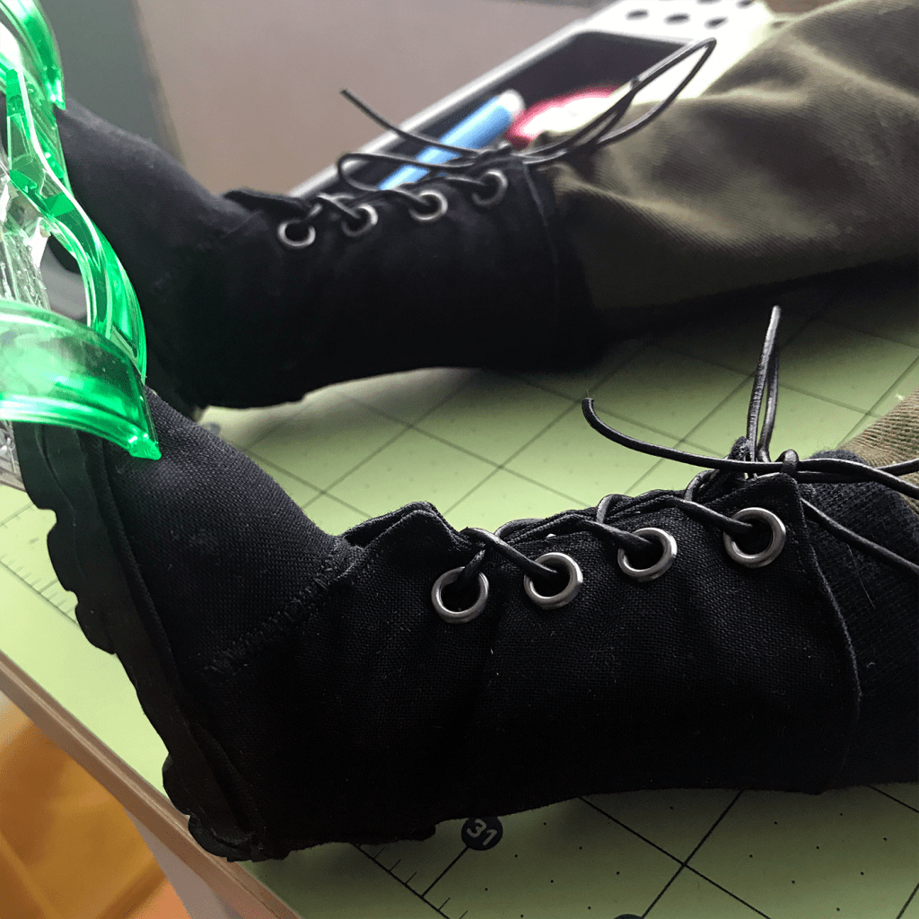 Magnus' black boots on his feet as they're being glued